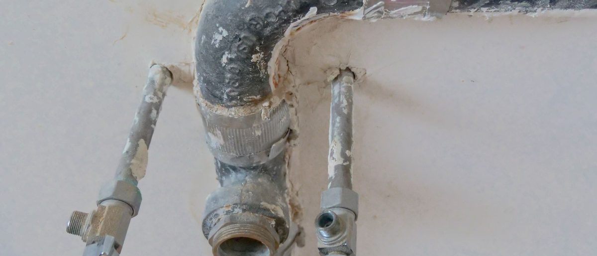 Exposed plumbing pipes running along an unfinished wall