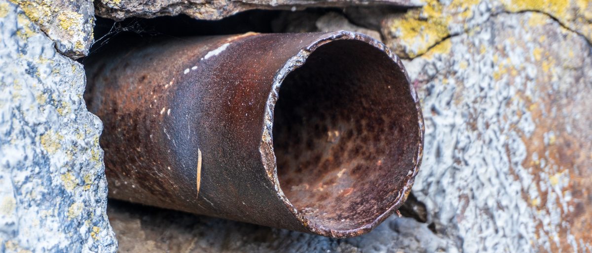 Pipe emerging from a hole cut in a stone wall